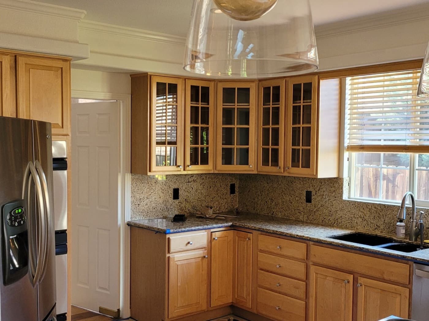 Kitchen with natural maple cabinets, glass uppers and a granite worktop