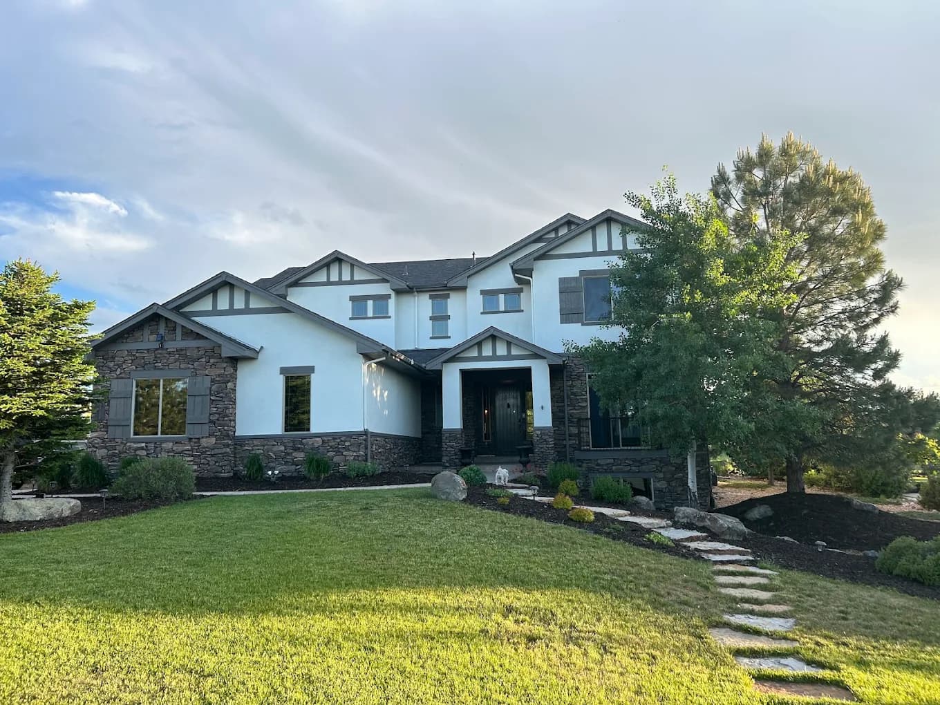 Gray craftsman home with a stone path, porch columns and fresh trim