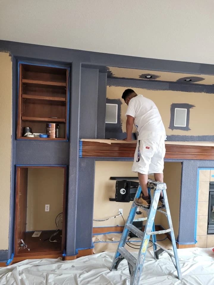 Helix painter on a ladder finishing a built-in fireplace wall