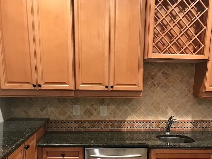 Kitchen with orange-toned oak cabinets and a tumbled stone backsplash