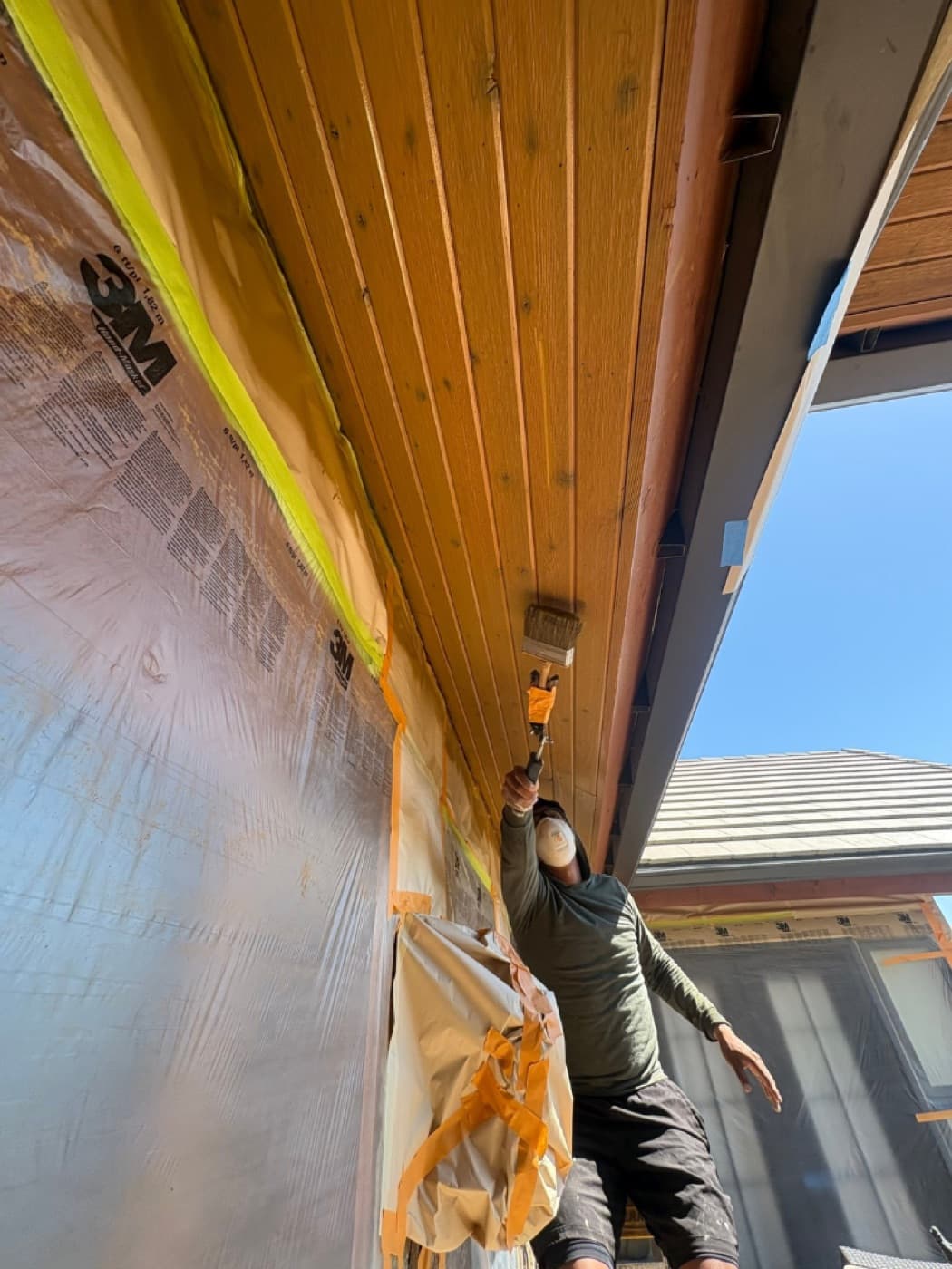 Painter brushing stain into a tongue-and-groove soffit