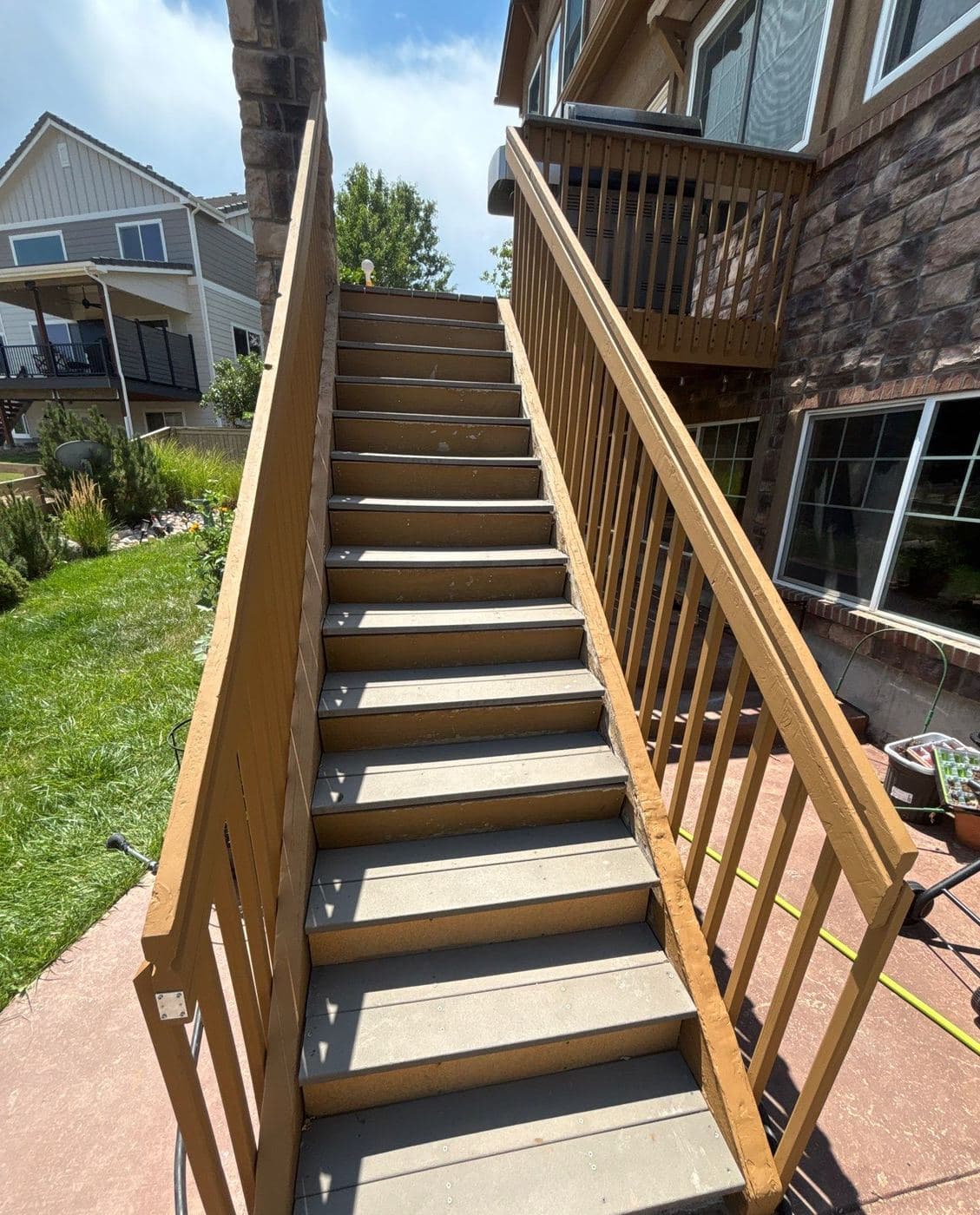 Deck staircase and railings finished in a warm stain, leading up to a raised deck