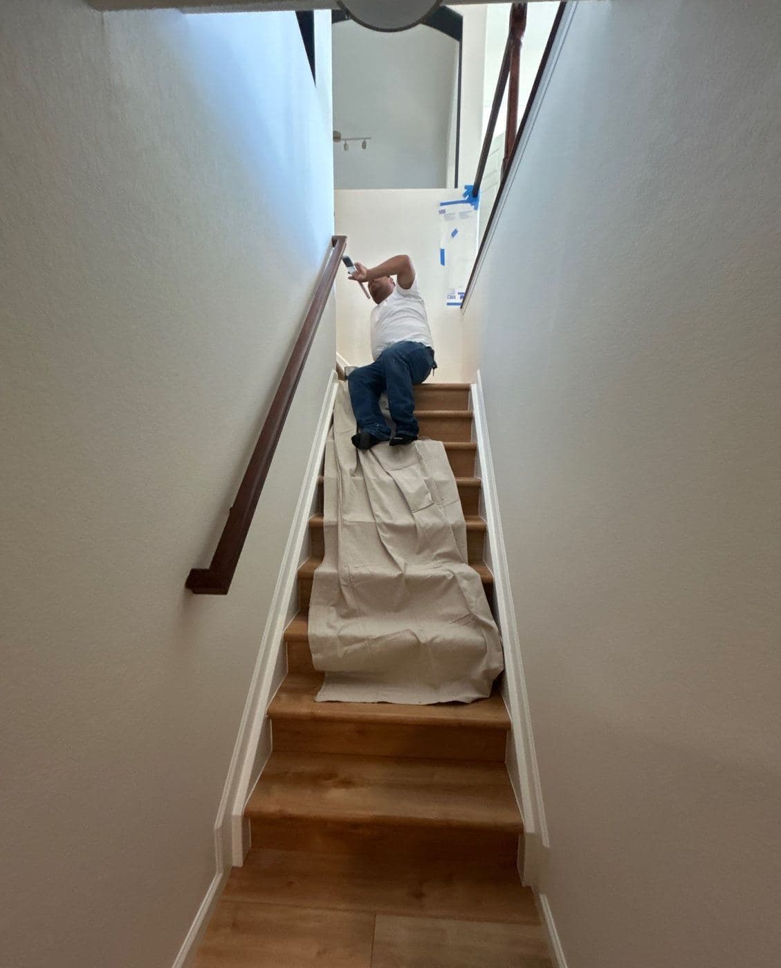 Painter working up a staircase with the treads covered