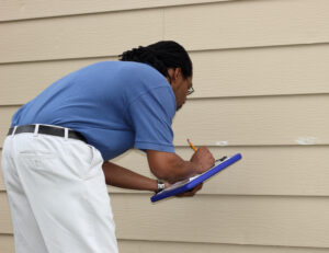 Insurance inspector looking at hail damage on siding